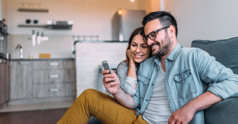 Imagen de primer plano de una pareja mirando en la pantalla de un smartphone en el salón de su casa