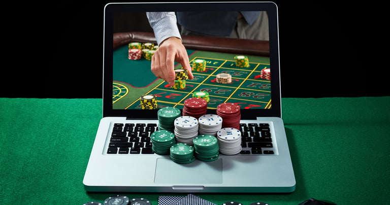 Una partida de póquer que aparece en la pantalla de un portátil con fichas de casino en el teclado.
