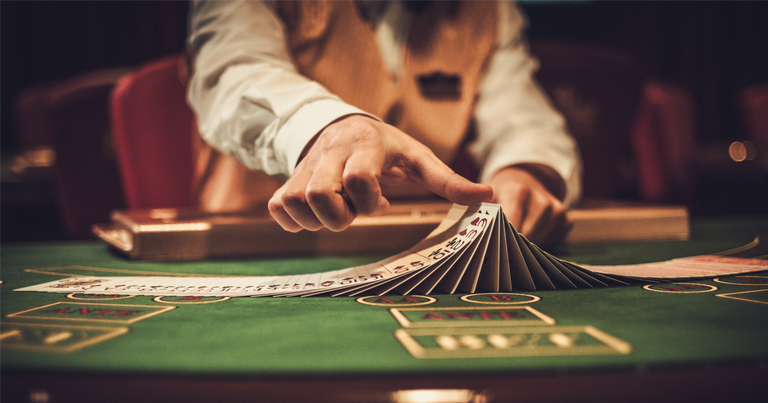Croupier detrás de la mesa de juego en un casino barajando cartas.